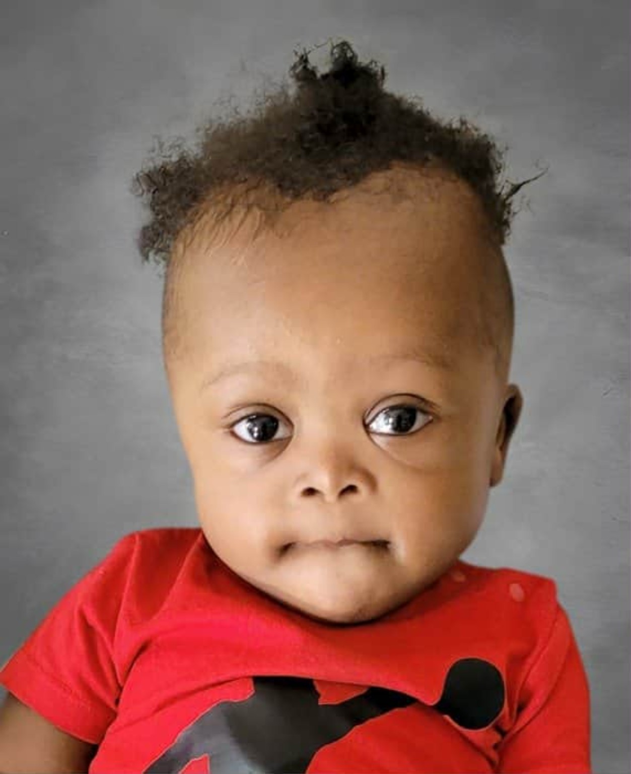 Hope-Divin Okundji, enfant souriant, vêtu d’un chandail rouge